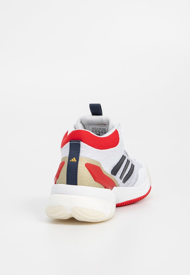 Zapatilla deportiva blanca con acentos en rojo y azul marino, parte superior texturizada, tres franjas negras y una suela blanca gruesa con un agarre de patrón.