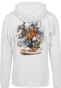 Biely mikina s grafikou, na ktorej je zobrazený basketbalista, basketbal a text "PRACUJ TVRDO, SNÍVAJ VEĽKO", doplnená o oranžové tenisky.