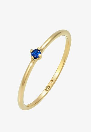 Inel din argint sterling placat cu aur, cu o piatră prețioasă albastră rotundă, având un brățară elegantă și un montaj cu patru colți. Marcaj "925" în interior.