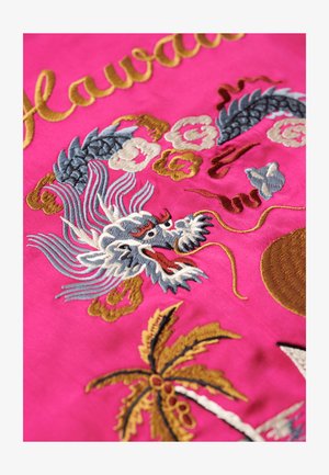 Rosa Stoff mit detaillierter Stickerei eines Drachen, Palmen und floralen Motiven in goldenen, blauen und weißen Fäden. Text "Hawaii" in Gold.
