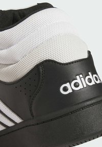 Czarny i biały zapiętek Adidasa z białą siateczką wyściółki oraz białym logo Adidasa na czarnej skórzanej paneli.