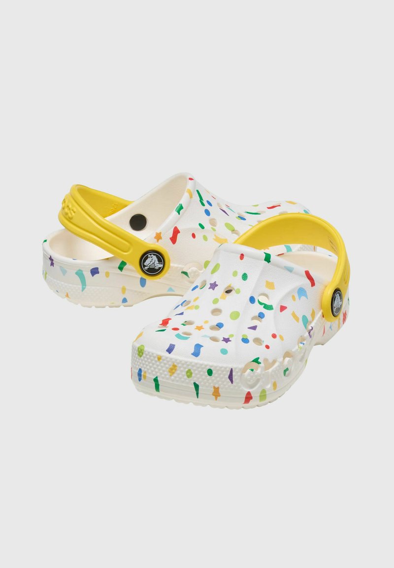 Weiße Clogs aus Gummi mit mehrfarbigen Punkten und Formen. Gelber Fersenriemen und runde Belüftungslöcher an den Seiten.