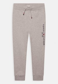 Harmaat collegehousut, joissa on joustava vyötärö ja nyörikiinnitys. Oikealla jalalla on tumma sininen "TOMMY HILFIGER" -logo pystysuoraan.