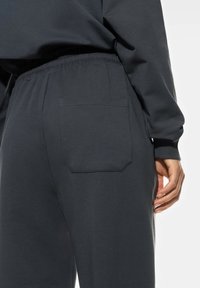 Grijze katoenen sweatpants met elastische tailleband. Beschikt over een enkele opgestikte zak op de achterkant, een soepele textuur en een relaxed fit.