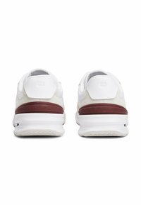 Scarpe da ginnastica bianche con una texture liscia, caratterizzate da un accento sul tallone color maroon e un logo "TOMMY HILFIGER" ben visibile sul retro.