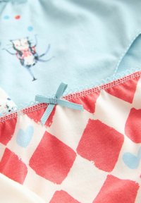 Kinderbekleidung mit einem hellblauen Oberteil mit einem Katzenmotiv und einem rot-weißen karierten Unterteil, akzentuiert mit einem blauen Band an der Naht.