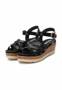 Sandalias de cuña negras de cuero, con tiras recortadas, hebilla en el tobillo, plantilla acolchada y suela de plataforma de color claro.