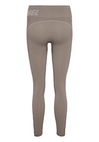 Leggings a coste beige con vita alta. Presentano cuciture bianche e un dettaglio del logo sulla vita. Materiale aderente ed elastico.