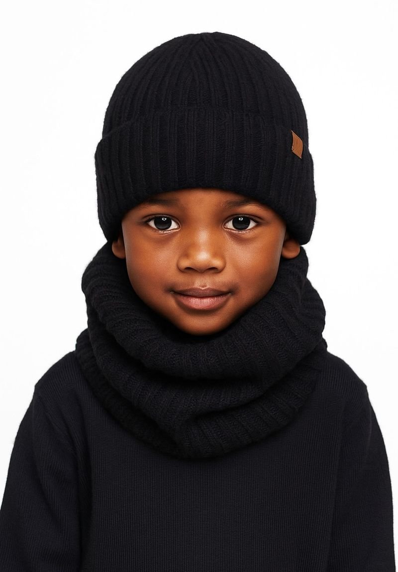 Black knit beanie with ribbed texture and a leather accent, paired with a matching ribbed black scarf. Both accessories are snug-fitting.