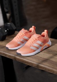 Lightweight athletic shoes in coral pink mesh with white stripes, featuring a textured surface, padded collar, and contrasting black outsole.