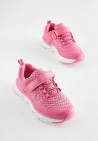 Baskets de sport roses avec une tige tricotée, texture en maille, sangle ajustable et semelle en caoutchouc blanche, dotées d'un embout renforcé bien visible.