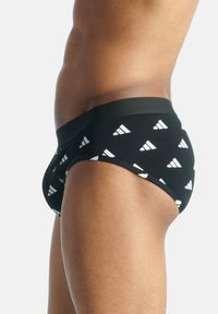 Schwarze Unterhose mit einem soliden Bund, der ein wiederholtes weißes Dreiecksmuster aufweist. Der Stoff wirkt weich mit einer glatten Textur.