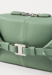 Borsa verde in pelle con hardware argentato, finitura texture, cuciture visibili e un dettaglio con cinturino attorno al corpo.