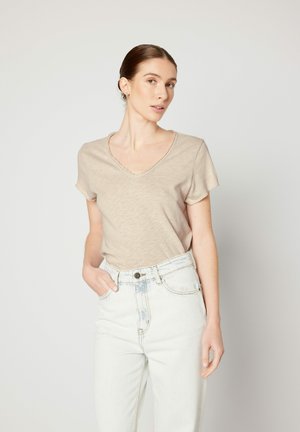 Beige V-hals t-shirt med korte ærmer, lavet af let stof, sat sammen med højtsiddende lysvaskede denim jeans. Minimalistisk design.