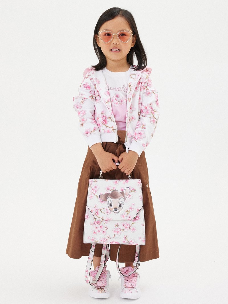 Sudadera blanca con estampado floral y volantes, camiseta gráfica rosa, falda marrón y bolso floral con un diseño de ciervo. Gafas de sol rosas en forma de corazón.