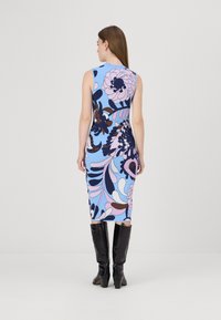 Φόρεμα με υφή και εφαρμοστή γραμμή, σε μπ�λε φόντο με έντονα λουλουδάτα μοτίβα σε ροζ, ναυτικό και καφέ χρώματα, συνδυασμένο με μαύρες μπότες ως το γόνατο.