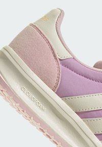 Rosa sneakers med en mjuk syntetisk ovandel, texturerade mockadetaljer, vit gummisula och "CLOUDFOAM"-logotyp på sidan.