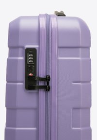 Valise rigide lavande avec surface texturée, double zip, verrou à code intégré et accents en métal noir contrastants.