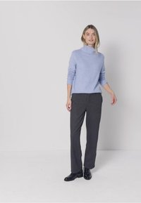 Light blue, turtleneck sweater paired with dark gray, wide-leg trousers. The outfit features a relaxed fit and smooth textures, complemented by black shoes.