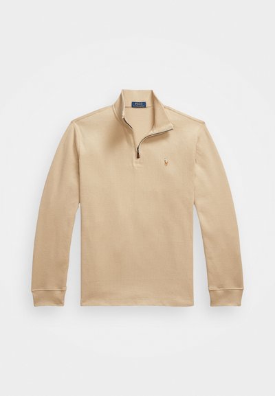Beige long-sleeve polo shirt with a zip neck, made of textured fabric, featuring a small embroidered logo on the left chest.