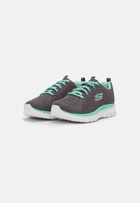 Scarpe da ginnastica in rete grigia con accenti turchesi, caratterizzate da una parte superiore testurizzata, suola bianca imbottita e sottili lacci abbinati.