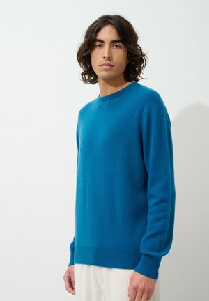 Blauer Pullover aus weichem Strickmaterial, mit langen Ärmeln, Rundhalsausschnitt sowie gerippten Bündchen und Saum.