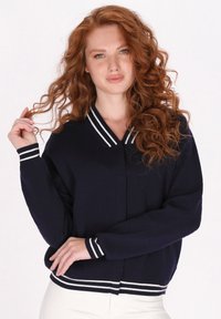 Cardigan blu navy con scollo a V e polsini e bordo a coste bianchi, caratterizzato da una vestibilità rilassata e tessuto a maglia testurizzata.