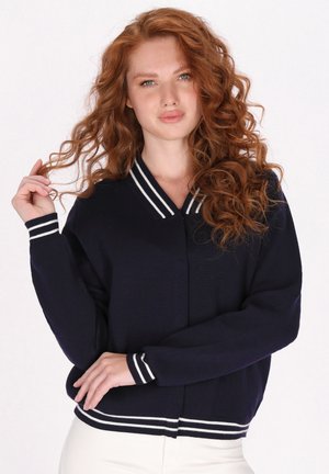 Námořnický cardigan s výstřihem do V a bílými pruhovanými ribbed manžetami a lemem, s uvolněným střihem a texturovaným pleteným materiálem.