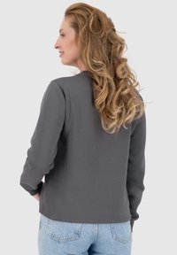 Grijze sweatshirt met lange mouwen en een ronde hals. Kenmerkt zich door een soepele textuur en een ontspannen pasvorm, in combinatie met lichtblauwe denim jeans.