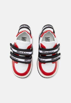 Baskets blanches et rouges avec des bandes Velcro noires et blanches portant le logo "Moschino", vues de dessus.