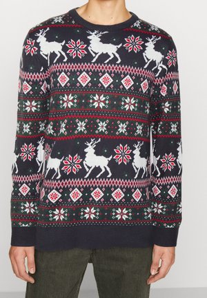 Pull en maille marine avec des rennes blancs, des flocons de neige et des motifs en losange rouges et verts. Col rond avec des poignets et un ourlet côtelés.