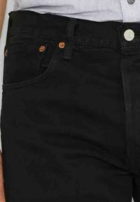 Zwarte denim jeans met een soepele textuur, vijf-pocket ontwerp en contrasterende stiksels. Metaalhardware bestaat uit een zilveren knoop en koperen klinknagels.