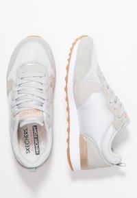 Ett par grå och vita Skechers-sneakers med gummisulor, nät- och mockadetaljer samt innersulor av "Air-Cooled Memory Foam", visade från ovan- och sidovy.