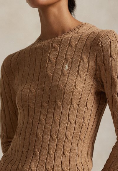 Világosbarna fonott mintás pulóver, kerek nyakkivágással és bordázott mandzsettákkal. Finom logó részlet a mellrészen. Texturált anyag.