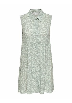 Robe sans manches vert clair avec motif de feuilles blanches, boutonnage devant, col pointu et jupe à volants.