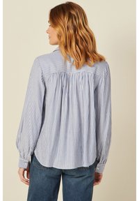 Blusa a righe blu chiaro e bianca con collo, caratterizzata da maniche lunghe e schiena arricciata per un fit morbido. Tessuto in cotone soffice.