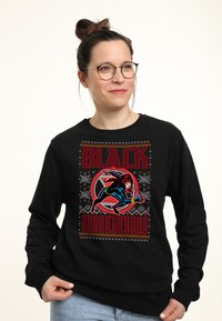 Sudadera negra con un gráfico de Black Widow, que presenta elementos de diseño en rojo y azul, texto en negrita y patrones de copos de nieve blancos.