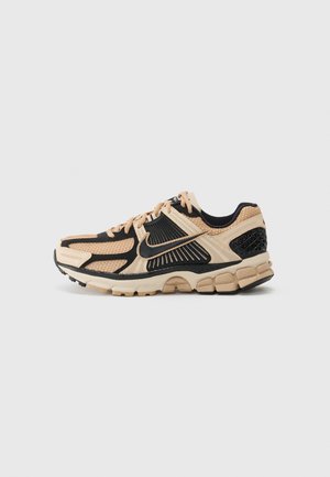 Nike sneakers met een beige en zwart mesh bovenwerk, rubberen zool en gestructureerde accenten. Gevoerde tussenzool voor ondersteuning en comfort.