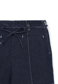 Pantaloni in denim blu scuro con cuciture bianche, un cordoncino legato a fiocco in vita e una cerniera silver visibile sul lato.