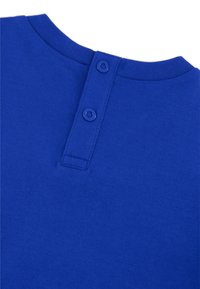 T-shirt in cotone blu con scollatura a girocollo, caratterizzata da due bottoni a pressione blu sul retro vicino alla scollatura e una texture liscia.