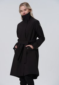 Zwarte, middellange jas met een hoge kraag, een ceintuur in de taille en twee voorzakken, gemaakt van gladde stof met drukknoopaccenten.