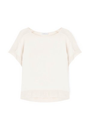 Luźna, kremowa bluzka z krótkim rękawem, okrągłym dekoltem i lekko zaokrąglonym dołem na białym tle.