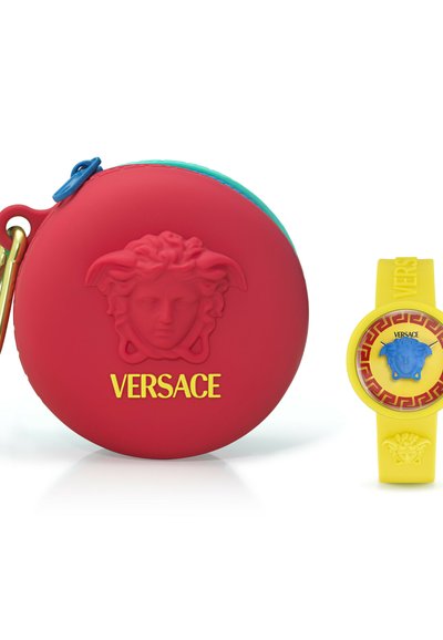 Estuche circular rojo con la cabeza de Medusa en relieve y el logo de Versace, al lado de un reloj amarillo de Versace con una cabeza de Medusa azul en la esfera.