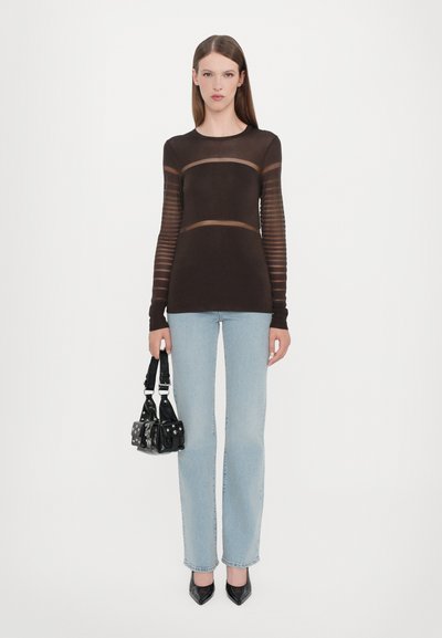 Brun tilpasset top med gennemsigtige stribede lange ærmer, parret med lys blå lige ben jeans og en lille sort taske med nitter.
