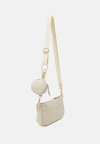 Gepolsterte beige Umhängetasche mit einem runden abnehmbaren Beutel, goldenen Beschlägen und einem weichen Stoffgurt. Verfügt über ein elegantes, schlankes Design.
