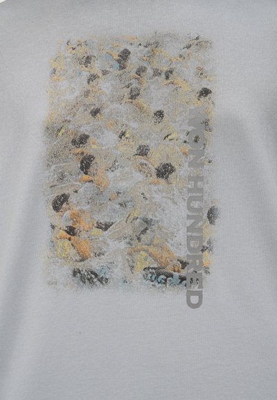 Θολή κολάζ ανθρώπων σε διάφορες πόζες με το κείμενο "WOHUNDRED" κατακόρυφα ευθυγραμμισμένο στη δεξιά πλευρά, σε ανοιχτό γκρι φόντο.