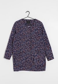 Maglione tunica a maniche lunghe con stampa astratta a leopardo blu, marrone e grigio chiaro, appeso a una gruccia nera su uno sfondo bianco.