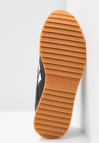 Czarny tenis z teksturowaną gumową podeszwą w kolorze pomarańczowym, z logo Reebok. Projekt obejmuje biały boczny akcent i gładki materiał wierzchni.