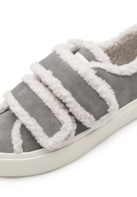 Scarpa slip-on grigia in suede con tre fasce soffici di colore crema. Presenta una fodera interna testurizzata e una suola in gomma bianca.