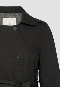 Schwarzer Trenchcoat mit strukturiertem Kragen, doppelt geknöpftem Verschluss und einem Stoffgürtel. Das Material ist glatt mit einem leichten Glanz.
